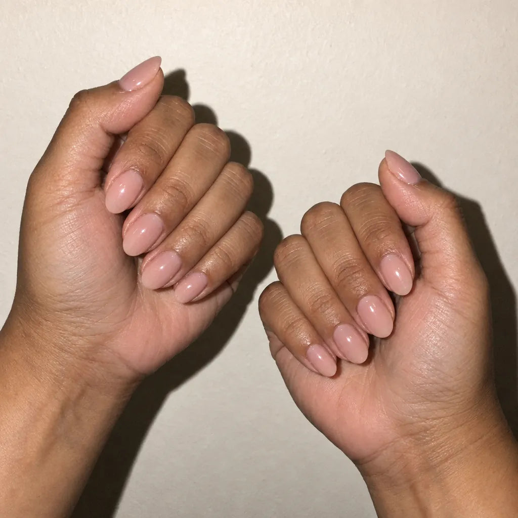 Short almond nails in a soft nude, hands resting on linen