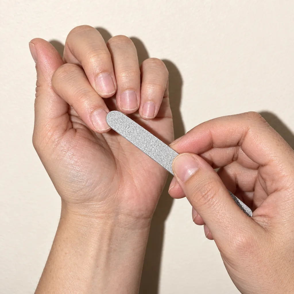 Hands buffing the shine off a bare nail with the kit’s silver file